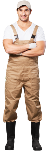Man in beige dungarees and white t-shirt with his arms folded.